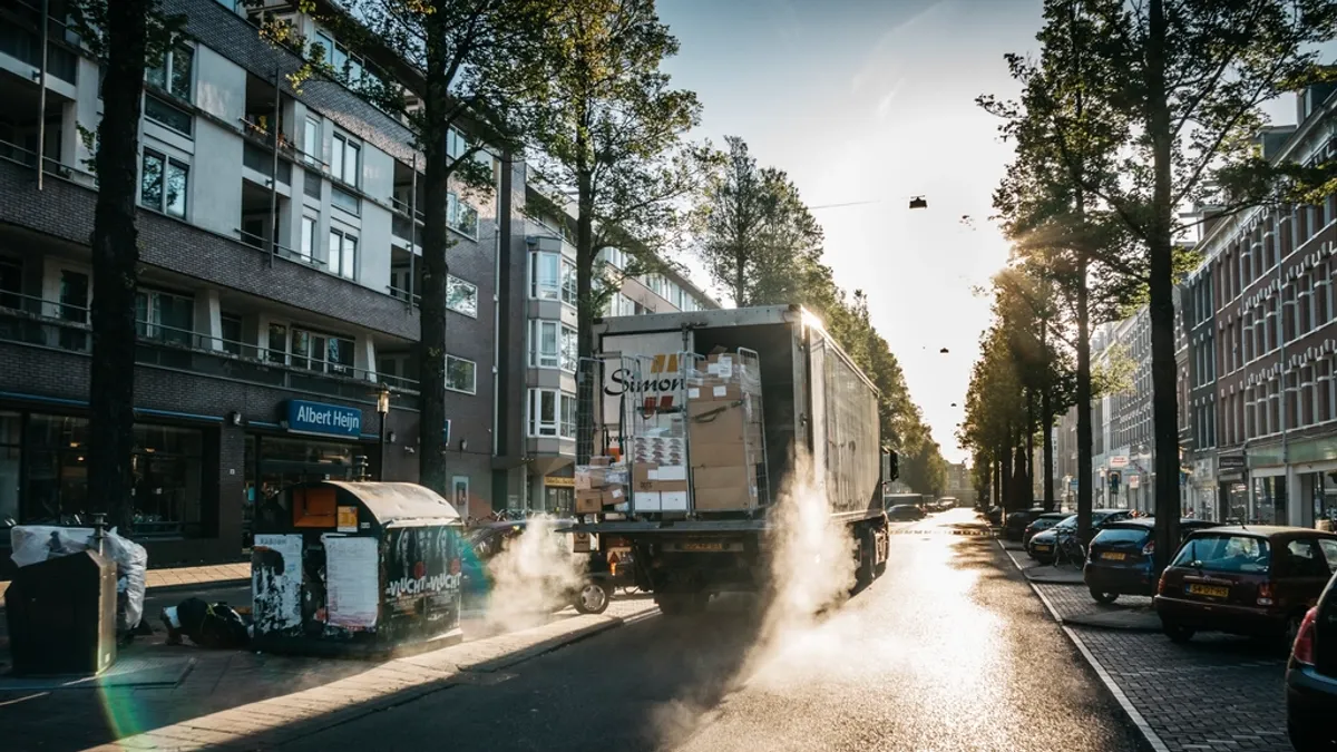 Bedrijfswagen rijdt door een natte stadsstraat
